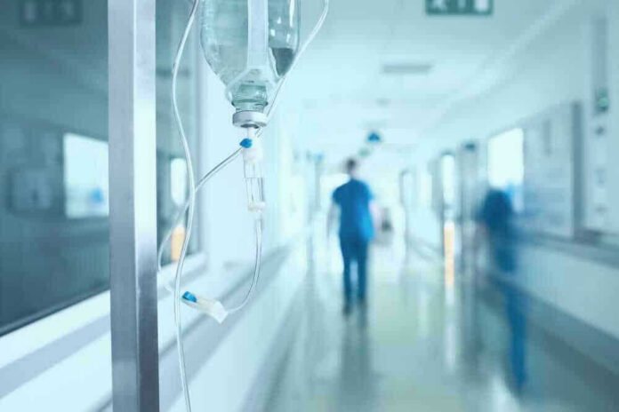 shutterstock_528854752-1-1 Hospital corridor with IV drip and healthcare worker.