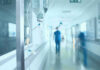 Invisible Ebola Wave Spooks Aid Chiefs Hospital corridor with IV drip and healthcare worker.