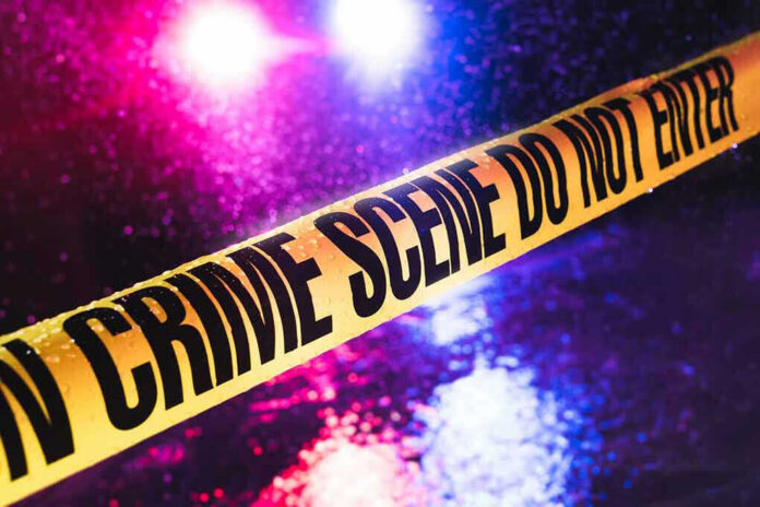 790342249-1 Crime scene tape with flashing lights in background.