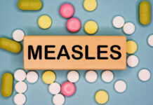 Measles Explosion Stuns America Wooden block with the word 'MEASLES' surrounded by various pills