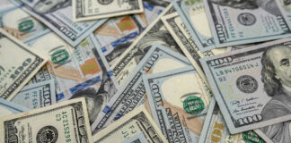 Scattered hundred dollar bills with Benjamin Franklins portrait.