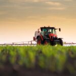 ALERT: Spike Wipes Out Farming Profits A tractor spraying crops in a field during sunset