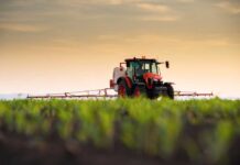 ALERT: Spike Wipes Out Farming Profits A tractor spraying crops in a field during sunset