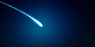 A bright comet streaking across a dark night sky filled with stars