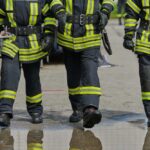 Three firefighters walking in uniform on a wet surface