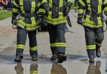 Wildfire Tragedy Takes Another Heroic Firefighter Three firefighters walking in uniform on a wet surface