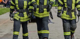 Three firefighters walking in uniform on a wet surface