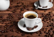 Coffee Shock: Heart Risk Drops Why? A white coffee cup filled with coffee on a wooden table surrounded by coffee beans