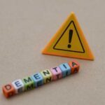 Colorful letter blocks spelling 'DEMENTIA' next to a warning sign