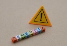 Colorful letter blocks spelling 'DEMENTIA' next to a warning sign