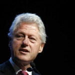 Clinton’s July Fourth Grenade Lands Man with gray hair speaking at an event.