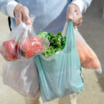 Deadly Lettuce Triggers BOMBSHELL Change Person carrying grocery bags with vegetables and fruits.