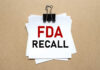 Glass In Frozen Treat? Check Your Freezer NOW! A notice labeled 'FDA RECALL' clipped to white papers on a brown background