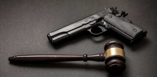 Pistol and judge's gavel on dark surface