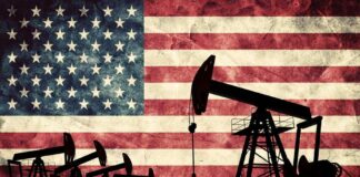 Silhouettes of oil pumps in front of a distressed American flag