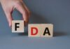 FDA CLASS I Recall Shocks Shoppers A hand holding a wooden block with the letter F, next to blocks spelling FDA