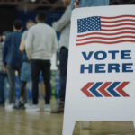 People in line next to Vote Here sign