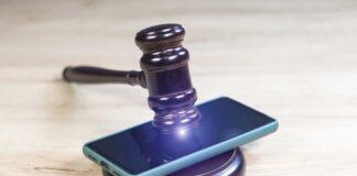 Judge’s gavel resting on a smartphone on a wooden surface