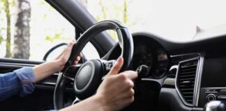 Hands gripping a steering wheel inside a car