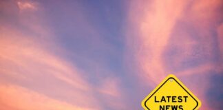 Yellow diamond sign reading latest news against a colorful sunset sky