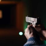 Hands aiming a pistol at an indoor shooting range