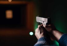 Armed Lurker Shadows Trump Golf Plans Hands aiming a pistol at an indoor shooting range