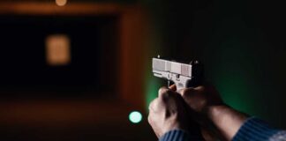 Hands aiming a pistol at an indoor shooting range
