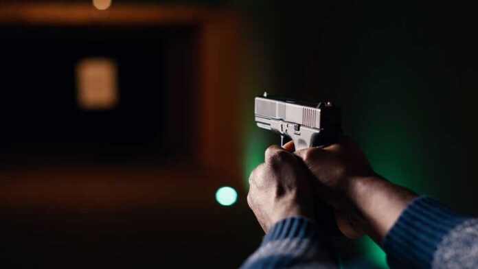 Hands aiming a pistol at an indoor shooting range