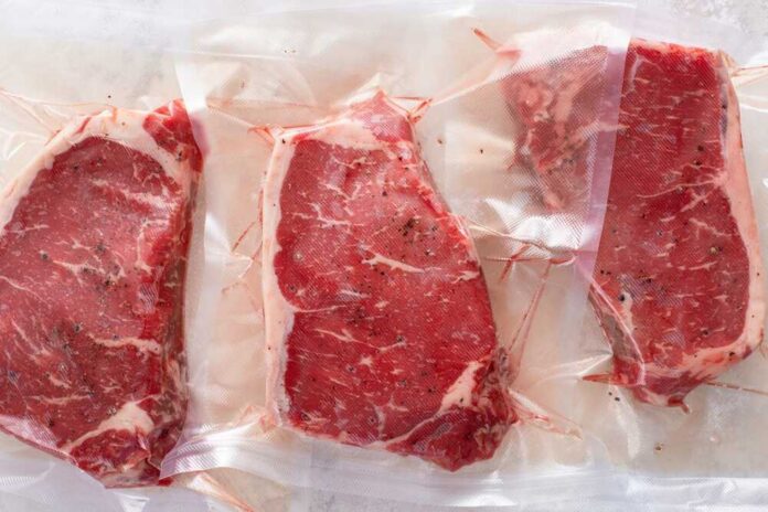 Raw,Beef,Steaks,Vacuum,Sealed,And,Ready,To,Be,Cooked Three vacuum sealed steaks on a white surface
