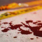 Two-Scene Bloodbath Stuns Nation Blood droplets on pavement near yellow caution tape