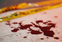 Two-Scene Bloodbath Stuns Nation Blood droplets on pavement near yellow caution tape