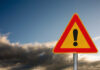 Grim Mine Find Shocks Nation A triangular warning sign with an exclamation mark against a cloudy sky