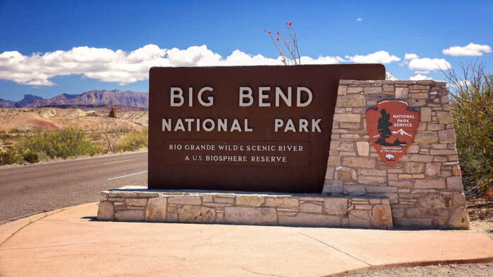Entrance,Sign,At,Big,Bend,National,Park,In,Texas Border patrol officer watches group sitting by a fence.