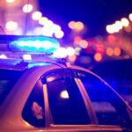In-N-Out Bloodbath Sparks More Questions Police car with flashing blue lights at night.