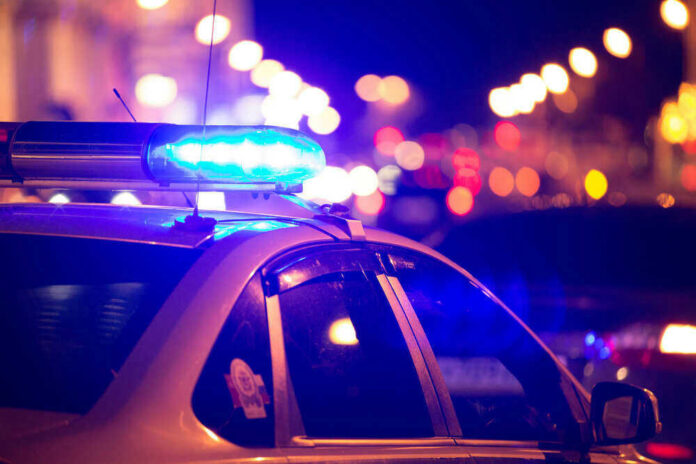 shutterstock_4489971131 Police car with flashing blue lights at night.