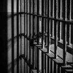 Black and white prison cell bars in dim light.