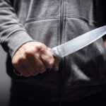 A person holding a knife in a threatening manner