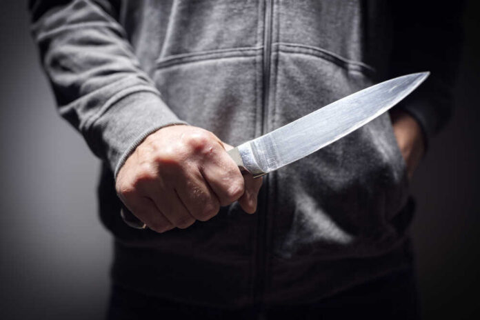 A person holding a knife in a threatening manner