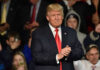 Trump Endorses Flock – Cities Revolt Man in suit clapping at public event.