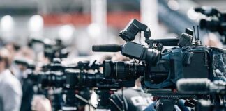 Broadcast cameras on tripods at a press event