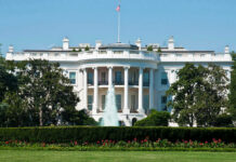 White House Ban EXPLODES – Court Showdown Next The White House, front view with fountain and flag.