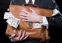 REPORT: Corruption Hits 20-Year High Person clutching leather bag with money sticking out.