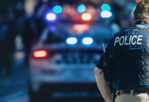 Campus Shock: Two Dead, Kratom Found Police officer stands near patrol car with lights flashing.