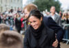 A woman smiling and interacting with a crowd.