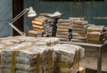 $10M Cocaine Stash Found WHERE?! Stacks of wrapped packages in a dimly lit warehouse