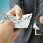 Funflation Strikes: Pay More, Play Less? A person handing over a stack of cash to another individual in a suit