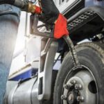 Person fueling a large truck with a gas pump