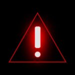 State Department Issues Travel Alert Red warning triangle with exclamation mark on black background
