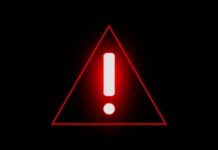 State Department Issues Travel Alert Red warning triangle with exclamation mark on black background