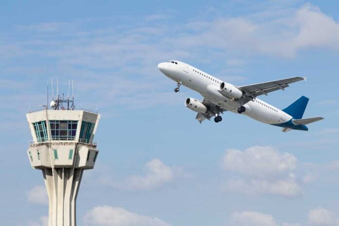 Air,Control,Tower,And,Airplane,On,Blue,And,Cloudy,Sky An airplane taking off near an airport control tower